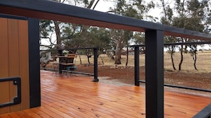 An outdoor wooden deck with a metal railing, a table, and chairs.