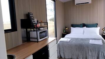 Ein Hotelzimmer mit Bett, Nachttisch, Mikrowelle und Blick ins Freie.