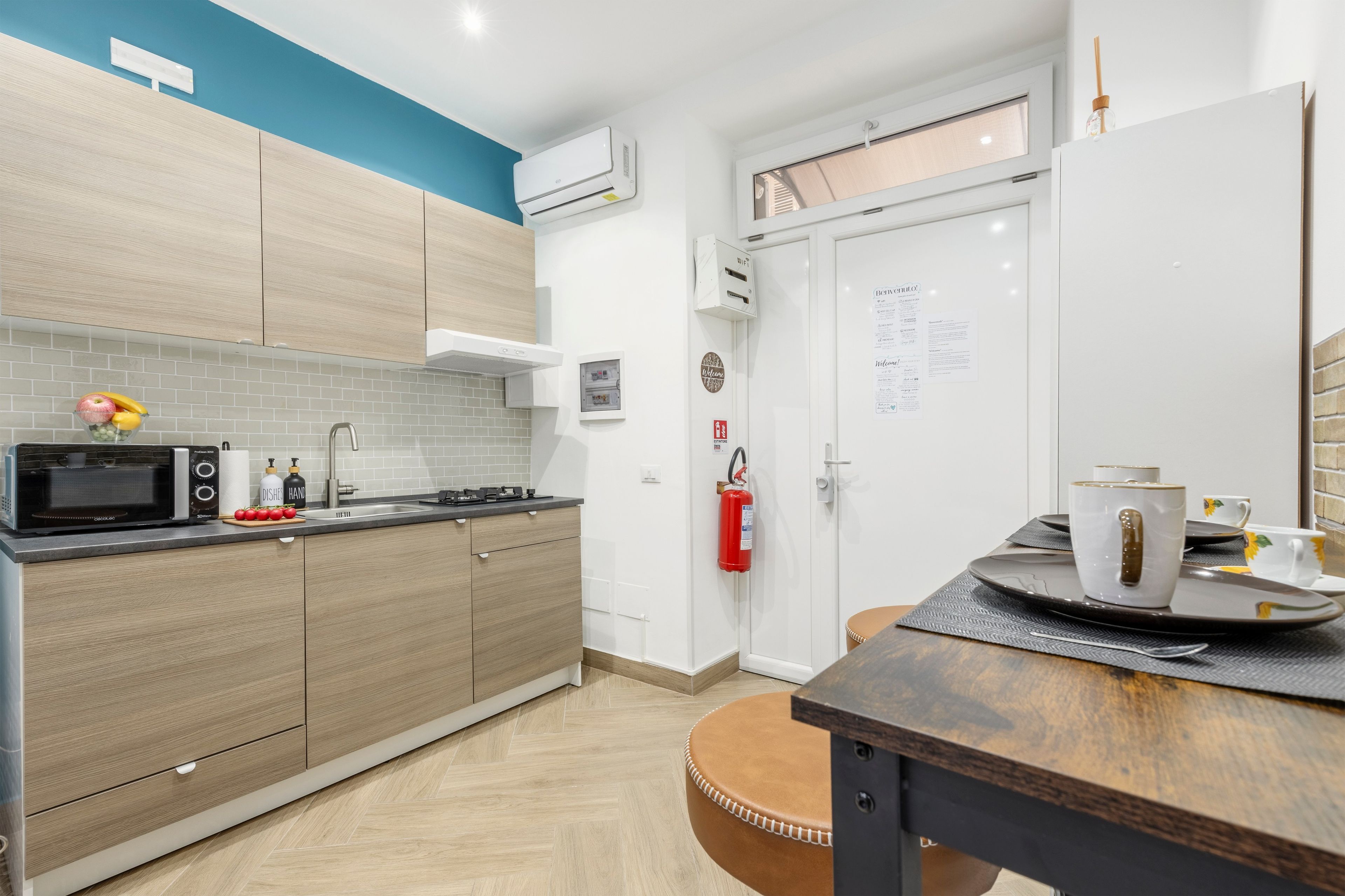 A modern kitchen with a microwave, stove, and a fire extinguisher.