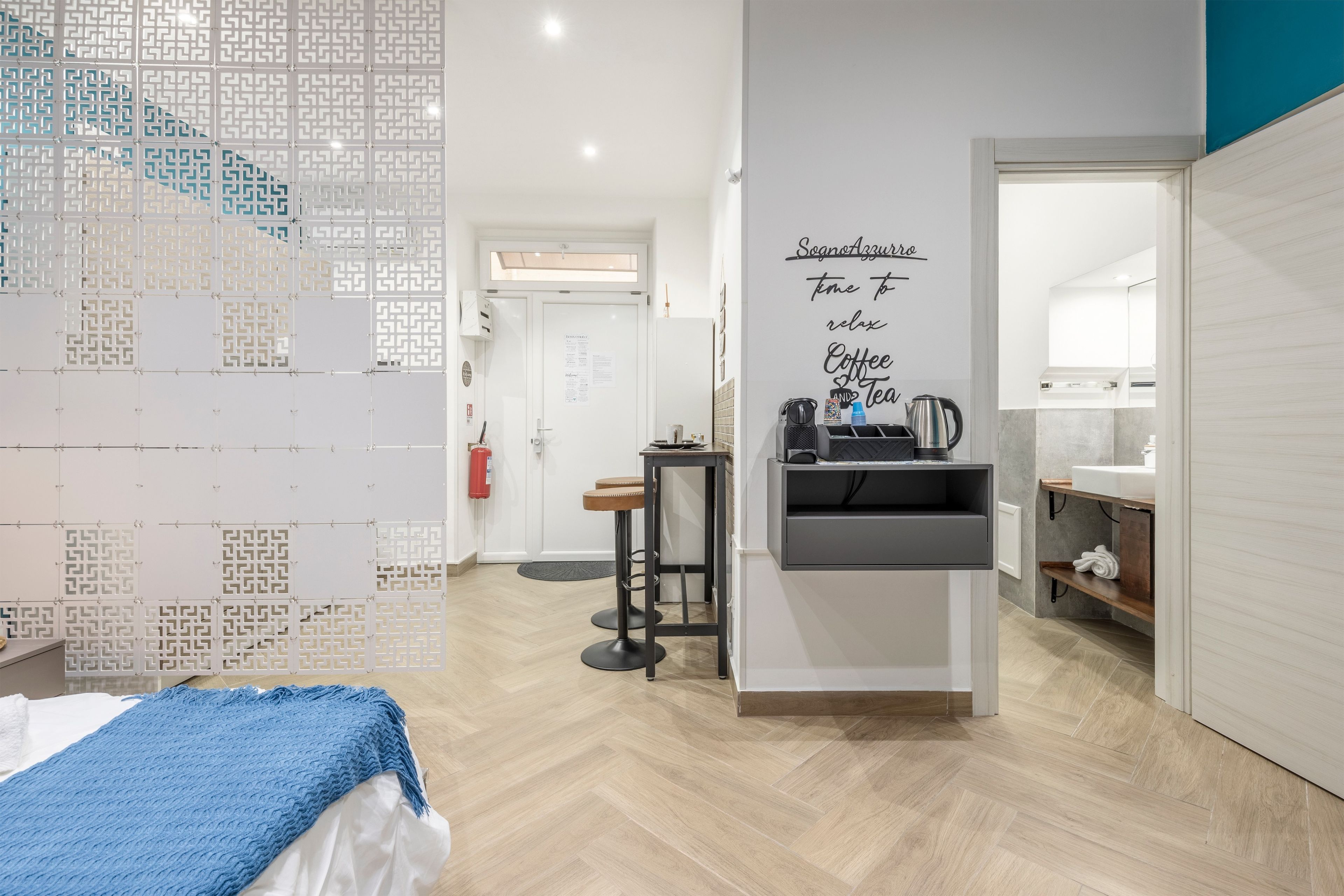 Une chambre d’hôtel moderne équipée d’un lit, d’une petite table, d’un coin café et d’une salle de bain avec un miroir.