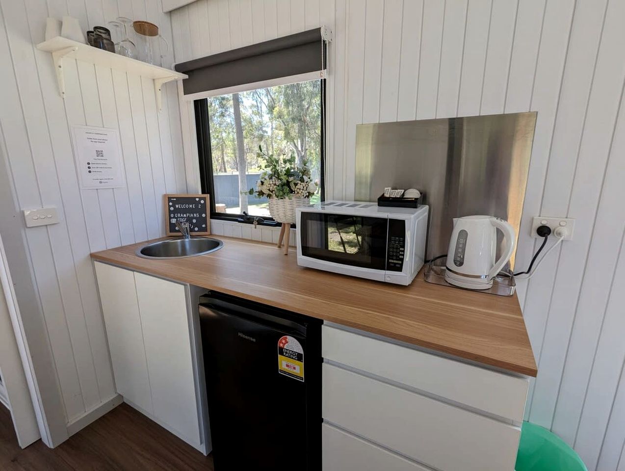 A compact kitchenette with a microwave, kettle, and sink.
