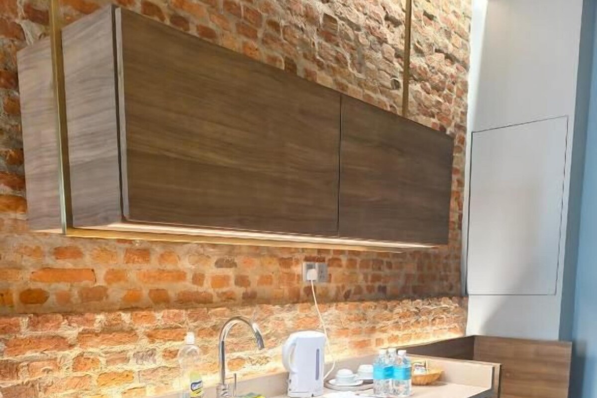 Eine moderne Küche mit Backsteinwand, Holzschränken und einer Arbeitsplatte mit Spüle.