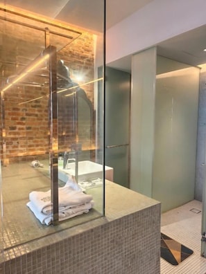 Ein modernes Badezimmer mit Glasabtrennung, sichtbarer Duschfläche und Fliesenboden.