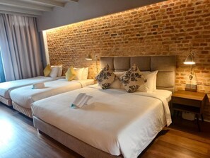 Ein Hotelzimmer mit Backsteinwand, zwei Betten mit weißen Laken und Nachttischlampen.