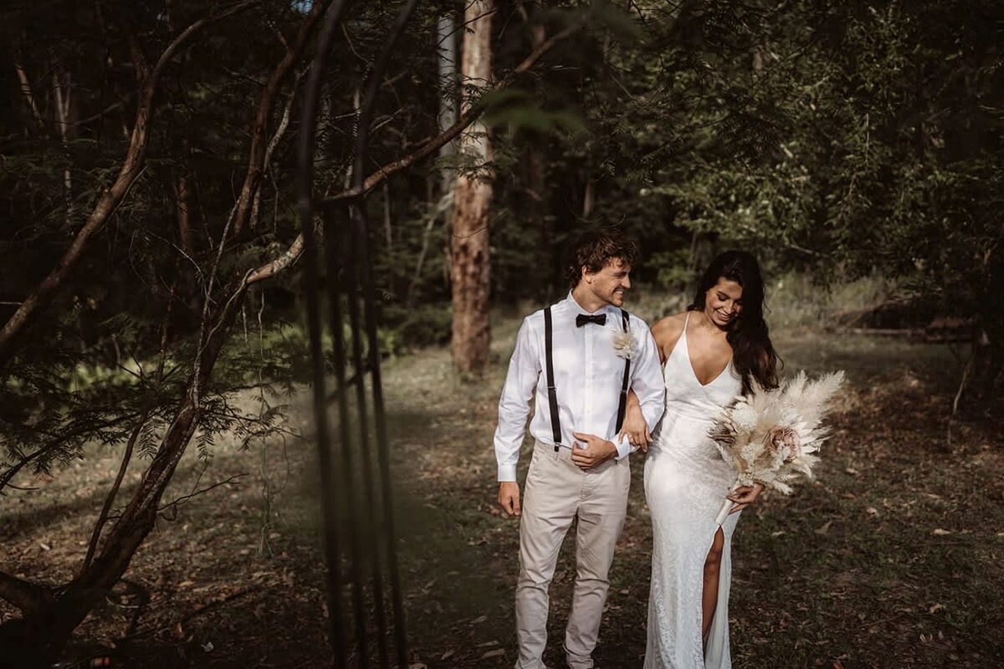 A forested area with a couple holding hands.