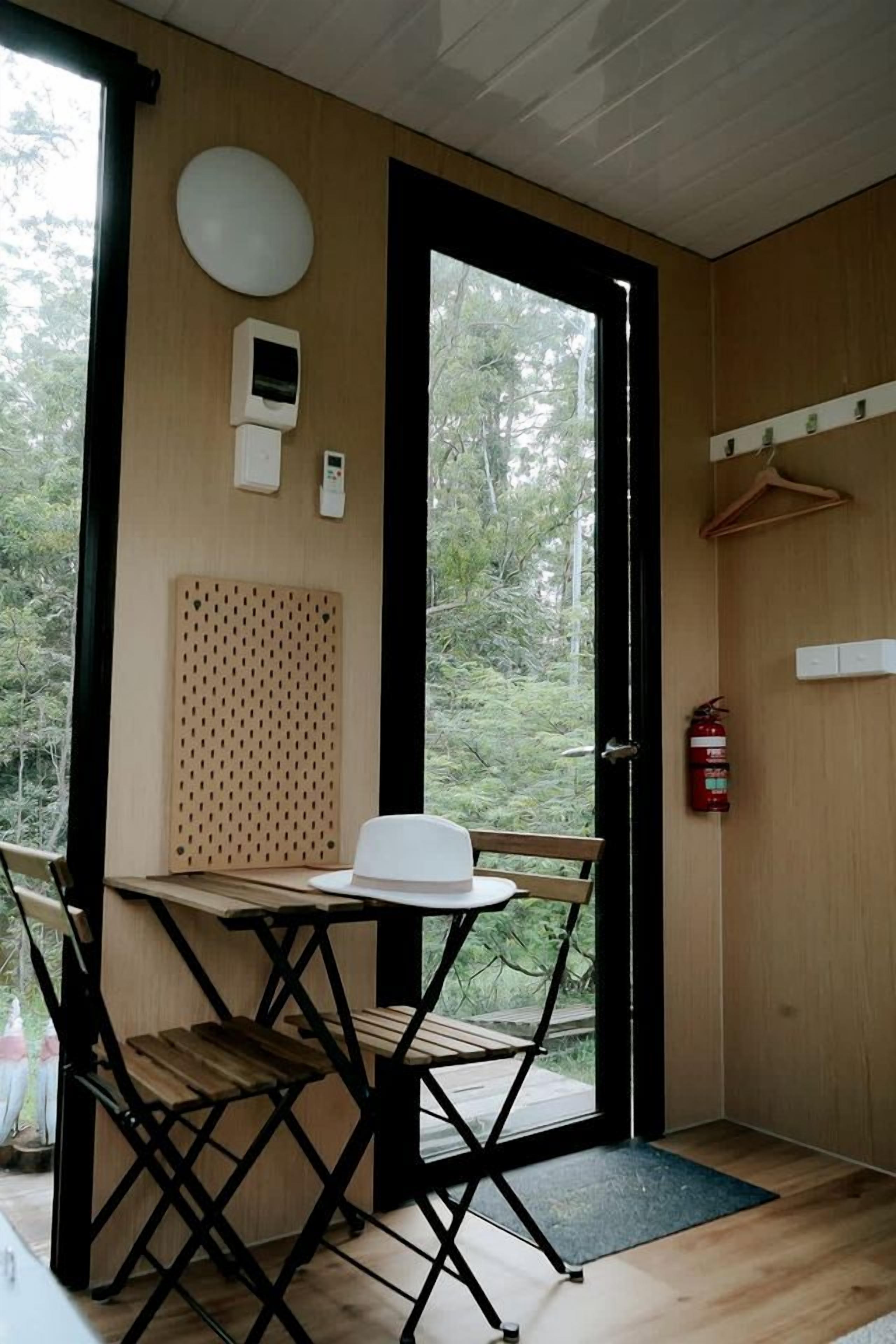 A room with a table and chairs, a fire extinguisher, and a door leading outside.
