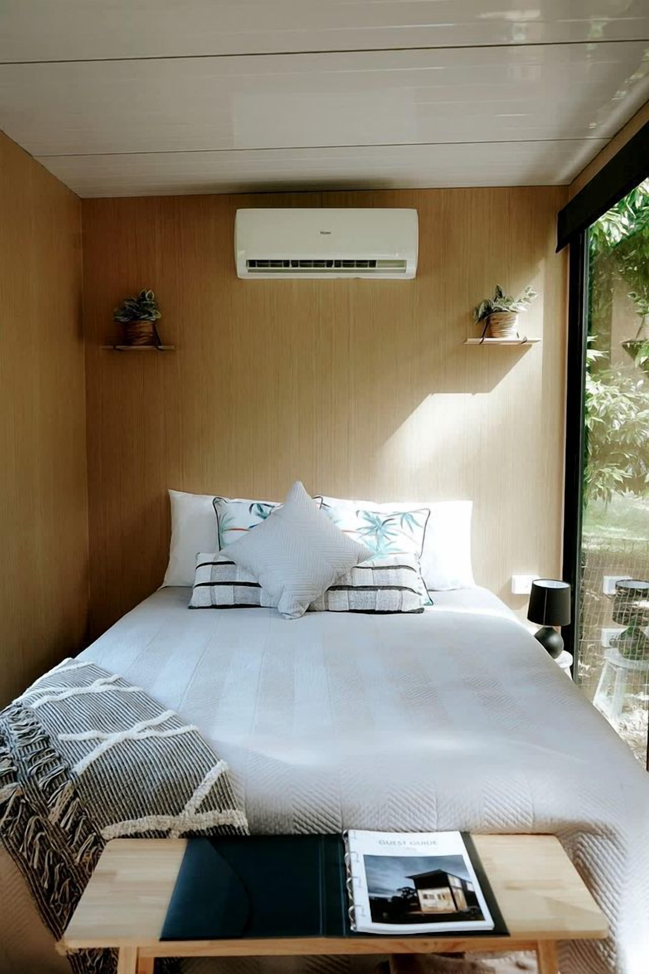 A bedroom with a bed, bedside table, and an air conditioning unit.