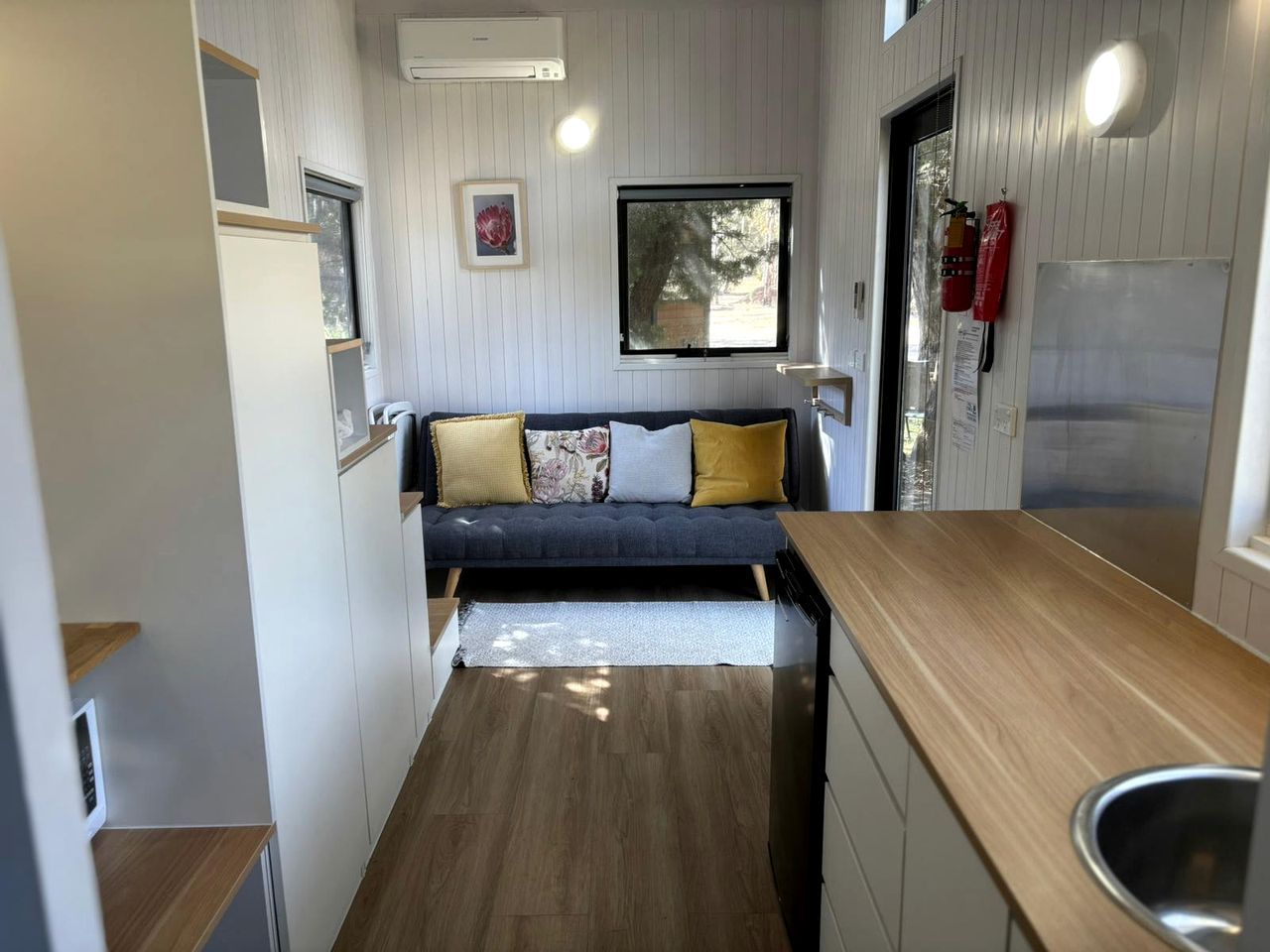 A compact kitchen with a built-in bench, wooden countertops, and a window providing natural light.