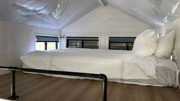 Une chambre à coucher avec un lit, une fenêtre et un plafond doté d’une surface réfléchissante.