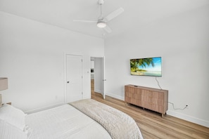 A bedroom with a bed, a ceiling fan, a TV on the wall, and a wooden cabinet. - Brand New, Minimalist and Spacious 4BR Retreat (Abilene)