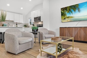 A modern living room with two grey sofas, a glass coffee table, and a wooden cabinet with a herringbone pattern. - Brand New, Minimalist and Spacious 4BR Retreat (Abilene)