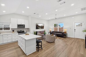 A spacious kitchen with white cabinetry, a central island, and a dining area with a sofa and table.