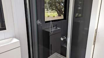 Une salle de bain moderne avec une paroi de verre, un lavabo et une fenêtre.