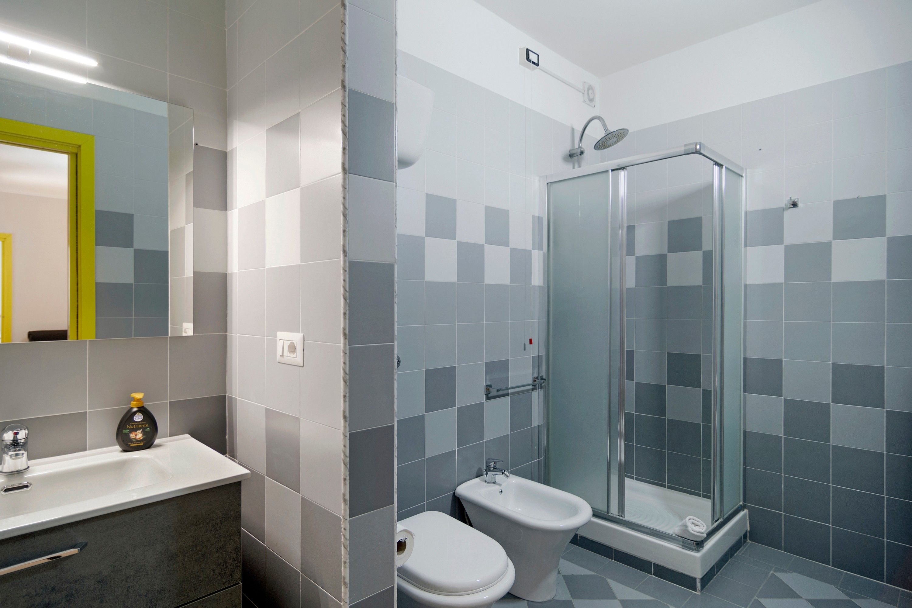 Un baño con cabina de ducha de vidrio, un inodoro y un lavamanos con espejo.