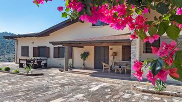 A house with a patio, outdoor furniture, and bougainvillea flowers.