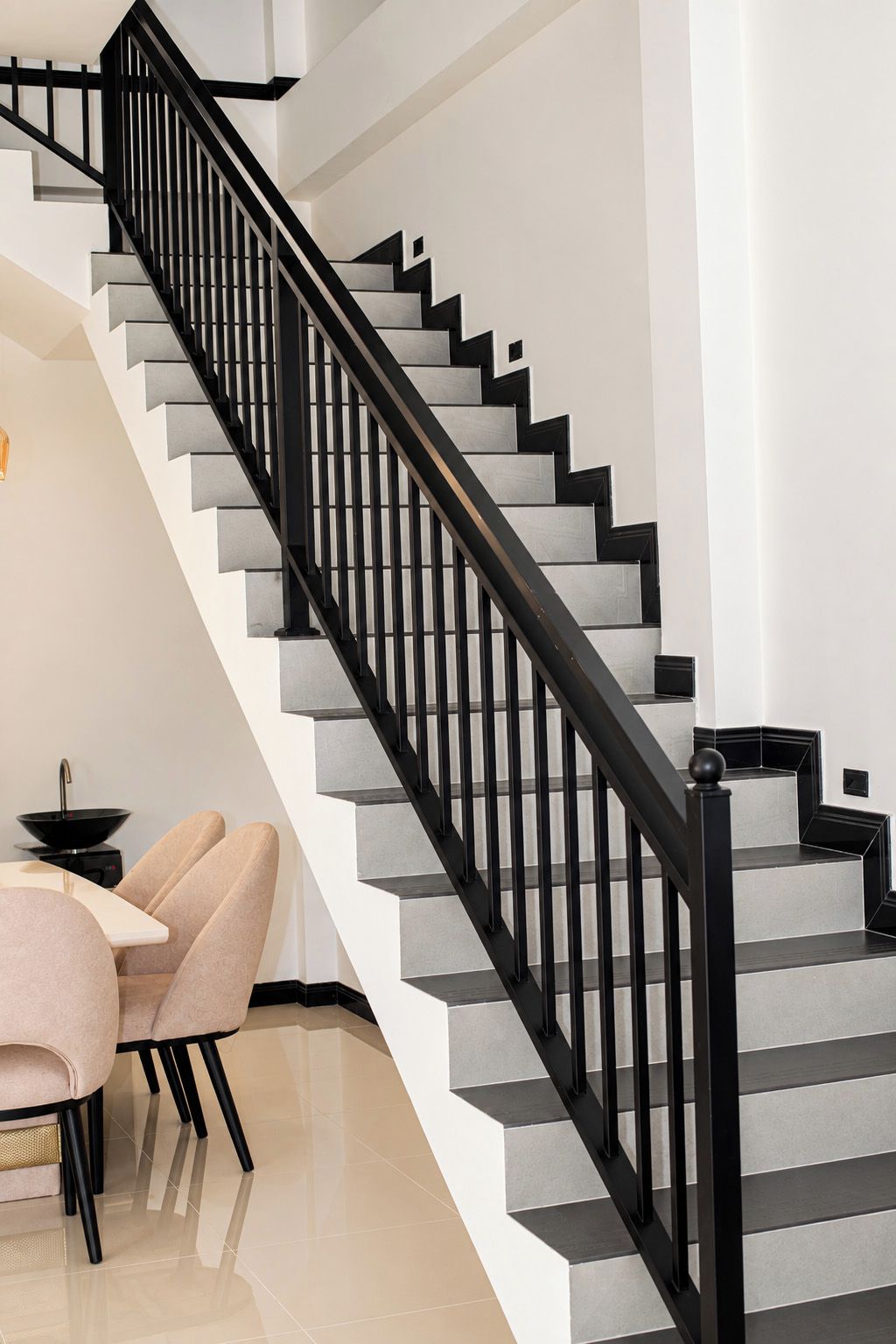 A staircase with black railings and grey steps, leading to an upper floor.