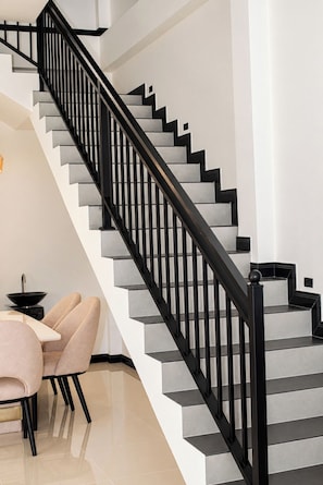 A staircase with black railings and grey steps, leading to an upper floor.
