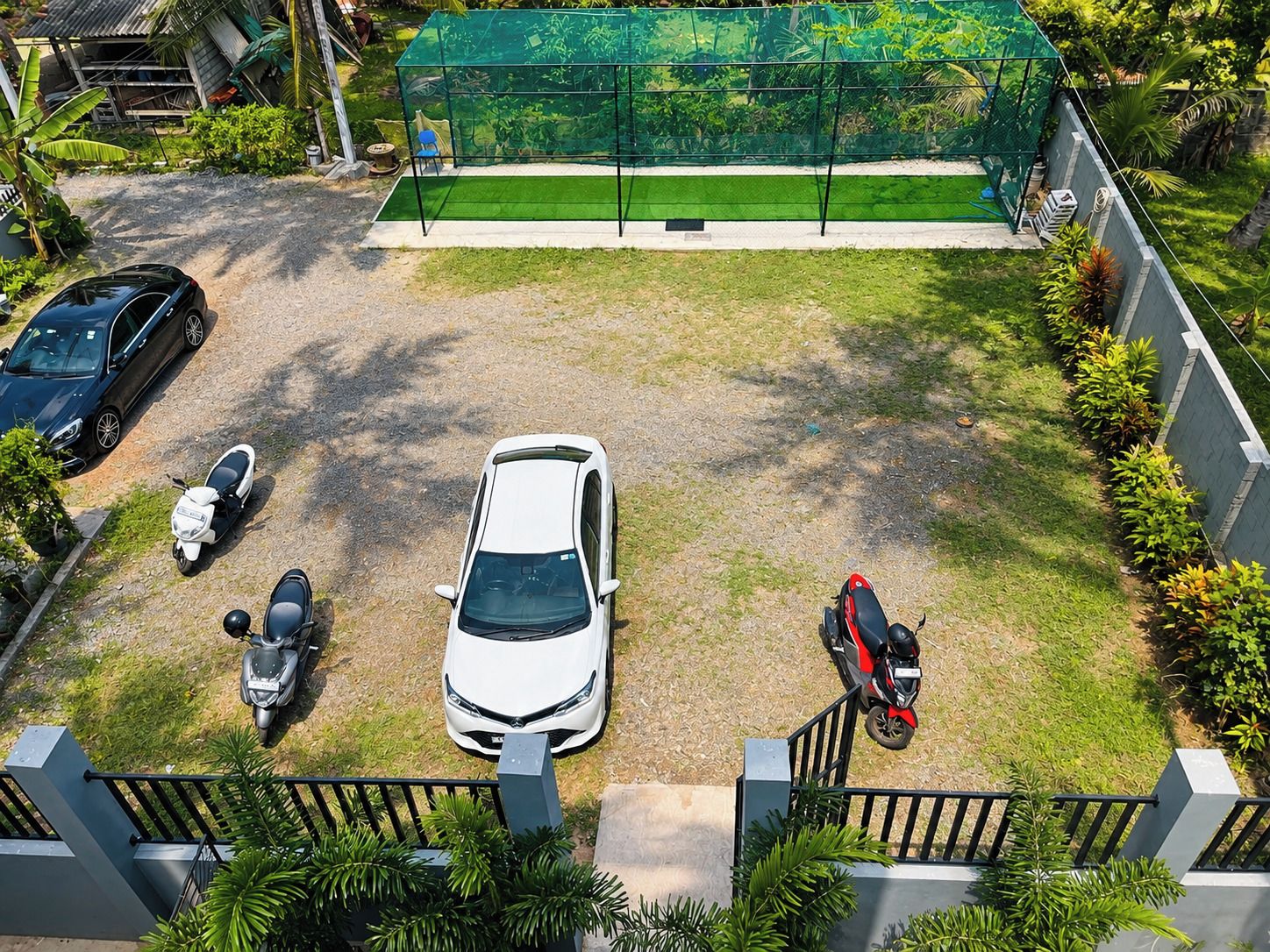 A parking area with a white car, a red scooter, and a black car.