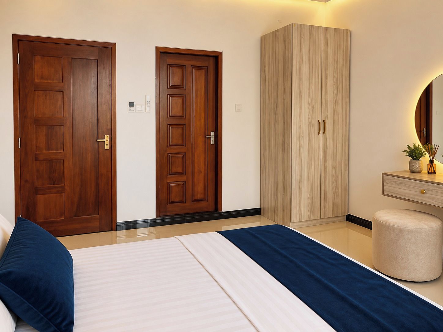Un dormitorio con una cama, dos puertas de madera, un armario, una tocador con espejo y un pequeño otoman redondo.