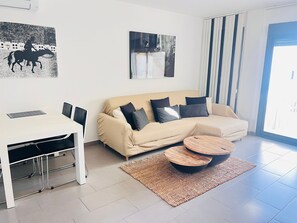 Ein modernes Wohnzimmer mit einer Couch, einem Couchtisch und einem Esstisch mit Stühlen.