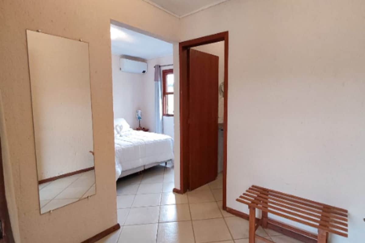 Un dormitorio con una cama, un banco de madera y una puerta que da a otra habitación.