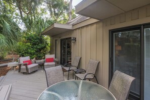 An outdoor patio with wicker furniture, a glass table, and a sliding glass door. - 518 Queen's Grant: Pet Friendly, 3BD/2.5BA/Hosts 8 (Hilton Head Island)