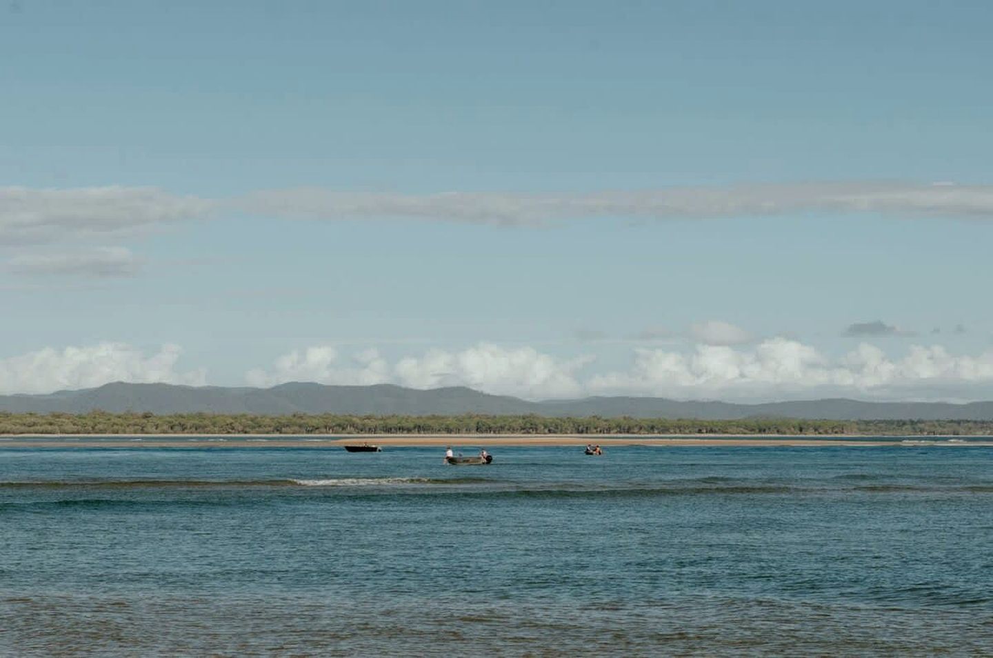 Una masa de agua tranquila con barcos y una costa lejana.