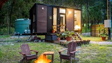 Una cabaña con porche, mobiliario exterior y un brasero.