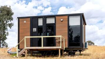 En modern, enplansstuga med träfasad, stora fönster och en veranda.