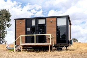 A modern, single-story cabin with a wooden exterior, large windows, and a deck.