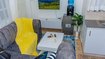 A living room with a sofa, a coffee table, and a television mounted on the wall.