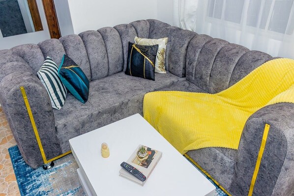 A grey sofa with yellow accents, a white coffee table, and a blue patterned rug. - An good place to be,with Mt Kenya view,a quiet place ,with a spacious parking (Nanyuki)