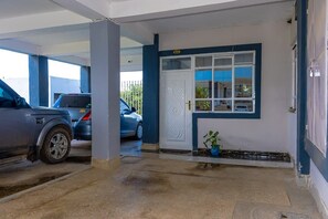 A parking garage with two cars parked, a white door with a window, and a potted plant. - An good place to be,with Mt Kenya view,a quiet place ,with a spacious parking (Nanyuki)