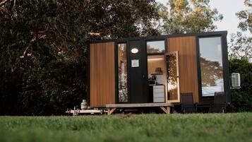 Una cabaña moderna y compacta con fachada de madera, una pequeña cocina y un área de comedor.