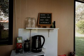 Placa de boas-vindas na Fazenda Makawata, uma cafeteira e uma chaleira em cima de uma mesa.