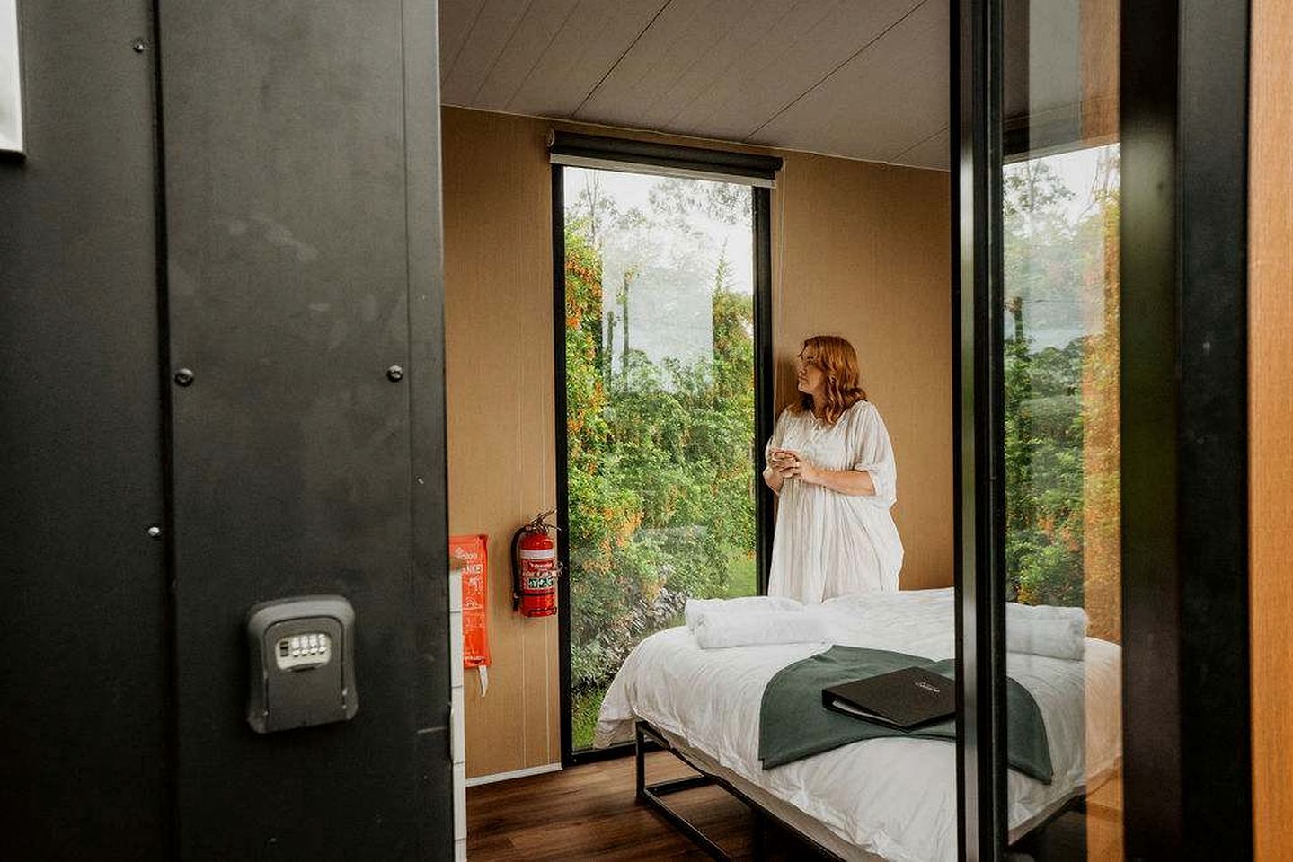 A room with a bed, a window, and a fire extinguisher.