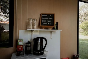 Une pancarte de bienvenue à la ferme de Makawata, une machine à café et une bouilloire sur une table.