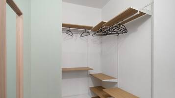 Ein begehbarer Kleiderschrank mit offenen Regalen, Holzboden und einer weißen Tür.