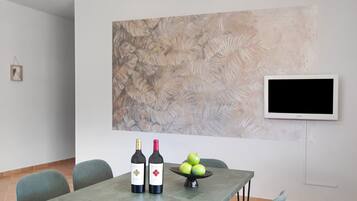 A dining area with a table, two wine bottles, and a bowl of apples.