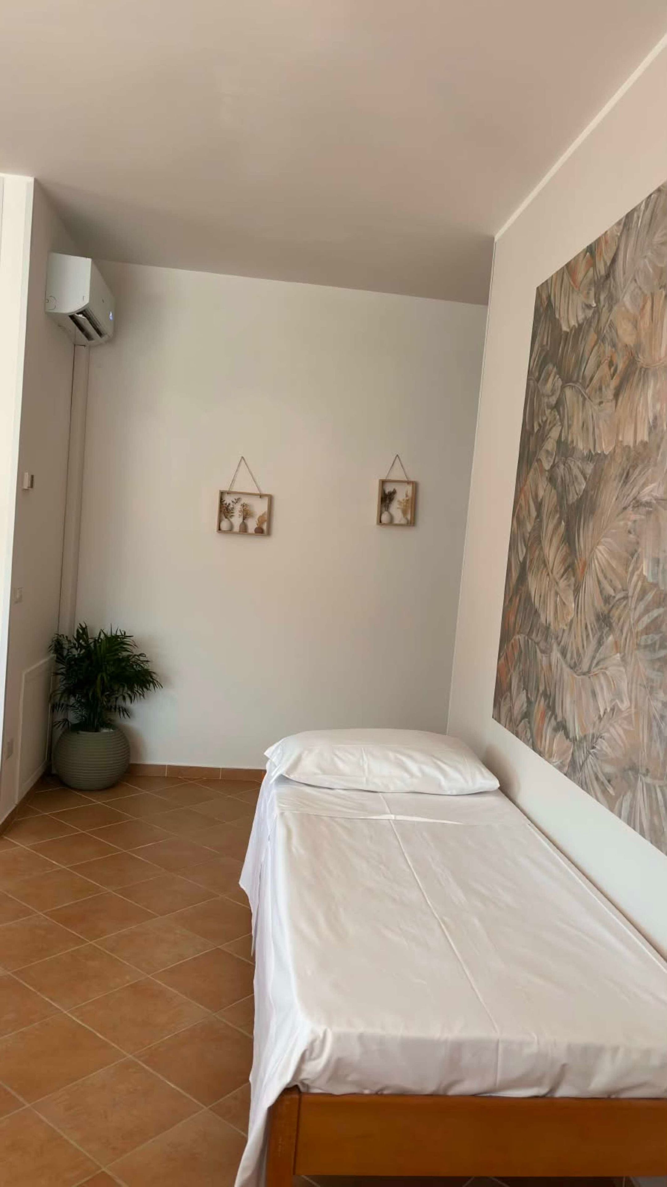 Un dormitorio con una cama, una planta en maceta y un aire acondicionado de pared.