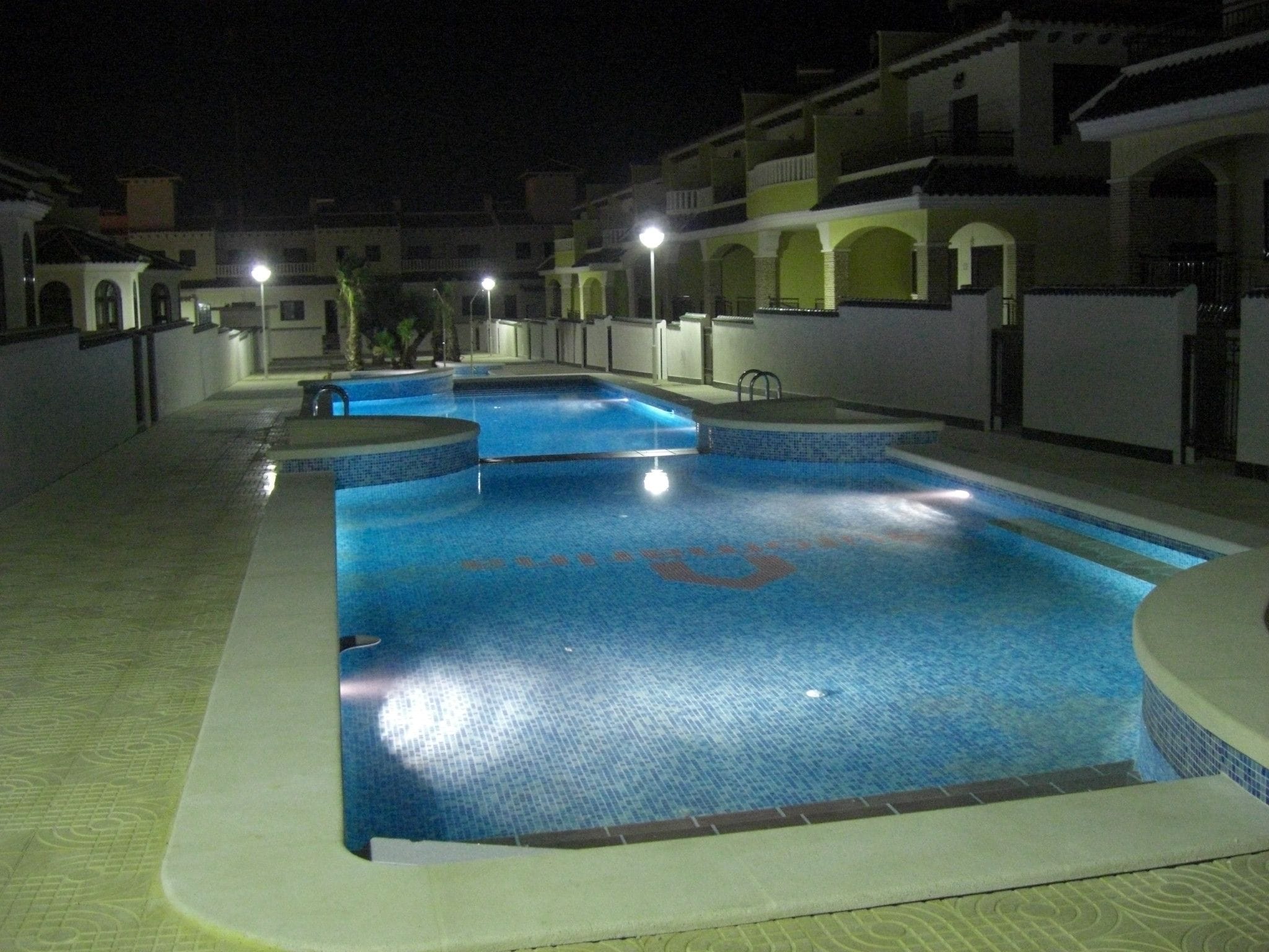 A swimming pool with a tiled deck and a poolside area.