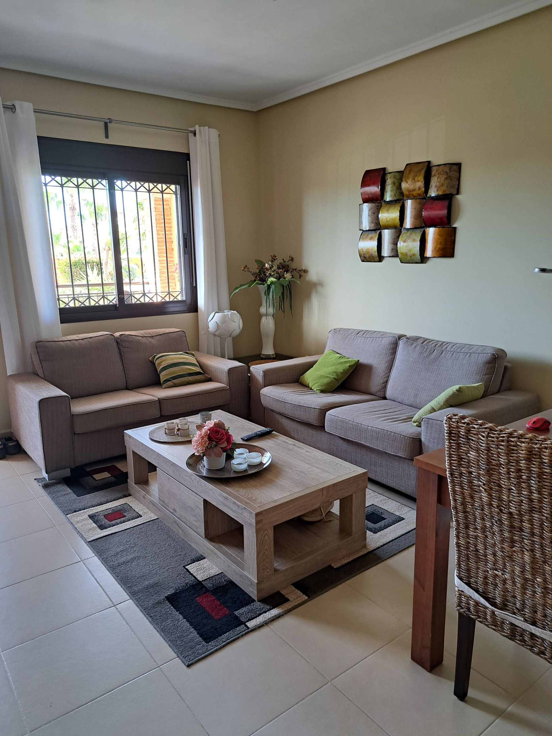Ein Wohnzimmer mit zwei Sofas, einem Couchtisch, einer dekorativen Vase und einem Wandbild.
