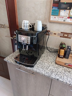 Een koffieapparaat op een granieten aanrecht, met een houten kast eronder.