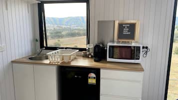 A compact kitchen with a view of the outdoors, a microwave, and a welcome sign.