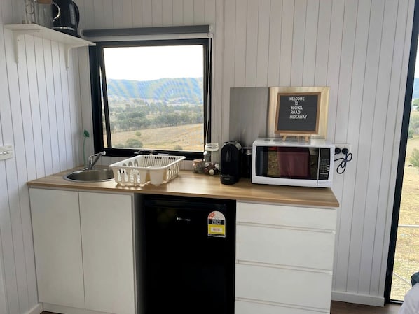 A compact kitchen with a view of the outdoors, a microwave, and a welcome sign.