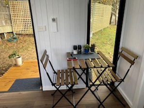 An outdoor wooden table with chairs, a potted plant, and a smartphone on the table.