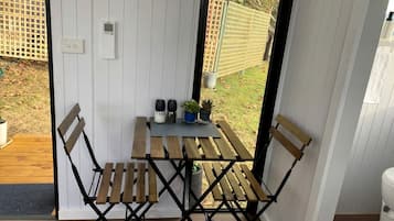 Ett träbord med stolar, en liten krukväxt och en väggmonterad apparat i ett rum med vita väggar och ett trägolv.