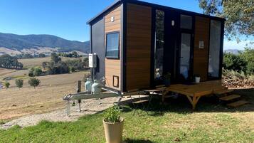 Una casa móvil moderna con techo plano, ventanas amplias y una zona de patio con mesa y sillas.