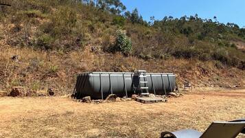 Un terreno seco y cubierto de hierba con una estructura cilíndrica grande que lleva la etiqueta 'INTERX' y una escalera que conduce a ella.