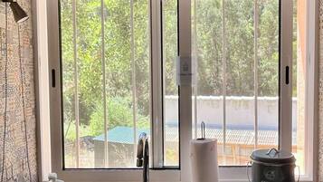Una cocina con un lavamanos de acero inoxidable, un contenedor de compostaje y una ventana con vistas a la vegetación.